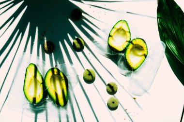 Avokado plastik bir torba üzerinde, vaccum mühürlü, tropikal bitki ile beyaz bir tahta üzerinde, ve sert gölge, Yeşil deniz kestanesi deniz kabukları ile