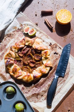 İncir galette bir tahta üzerinde bir pişirme kağıdı üzerinde pasta kabuk ve taze incir ile yapılan, üst görünümü.