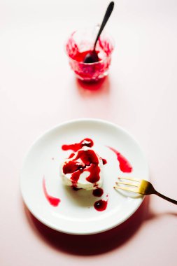 Pembe bir arka plan üzerinde beyaz bir çanak üzerinde raaspberry couls ile sert şekilli panna cotta