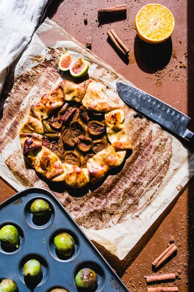 Figs galette made with pastry crust and fresh fig on a cooking paper over a wooden board, top view.