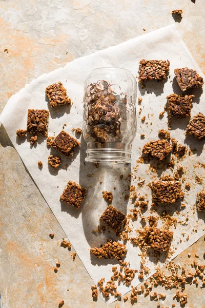 Healthy snack bar, typical   of russian diet, called kozinaki, made ith sunflower seeds and honey, on a wwhite food paper inside and outside a glass jar.