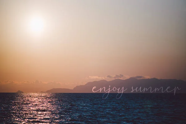 Amazing sunset on a seascape, with the emotional quote enjoy summer overimpressed with a text on layer,