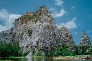 Arka plan bulut ve mavi gökyüzü ile kireçtaşı dağ toplayan manzara. Gölde tekne Park arka planda kayalık dağ ile kürek