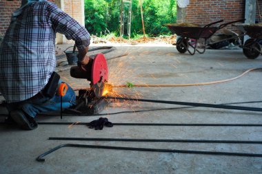 İşçi tarafından elektrik kesme makinesi inşaat sahasında güçlendirme çelik kesme. Parlak ışıktan çelik kesme makinesi.