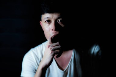 Kameraya bakarak ve dikkatli bir şekilde izole siyah arka plan ile bir şey düşünmek Asya düşünceli adam portresi