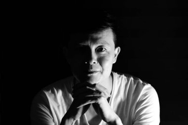 Tek renkli smilie ve izole siyah arka plan ile kameraya bakan Asya adam portresi