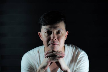 Kameraya bakarak ve dikkatli bir şekilde izole siyah arka plan ile bir şey düşünmek Asya düşünceli adam portresi