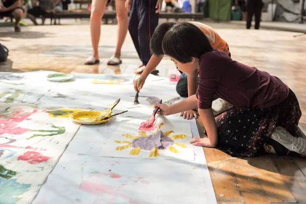 Portrait Asian little girl painting and drawing on the paper at outdoor art event for kids.