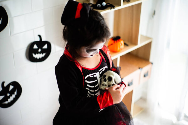 Portrait Asian little girl in Halloween costume holding the skull