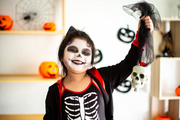 Portrait Asian little girl in Halloween costume holding the skull