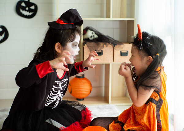 Portrait of two sisters in Halloween costume acting like a ghost frigthening expression to each other in Halloween festival