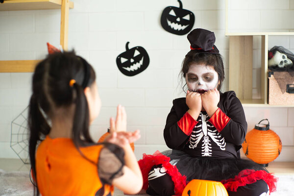 Portrait of two sisters in Halloween costume acting like a ghost frigthening expression to each other in Halloween festival