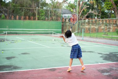 Asyalı kız eski açık tenis kortu tenis oynarken arka portresi