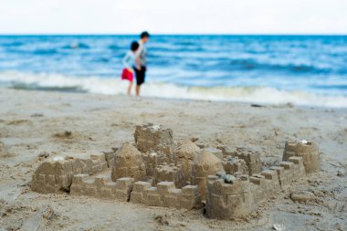 Bulanık kız ve arka planda sahilde yürüyüş büyükannesi ile kalıp kullanarak yerleşik sandcastle