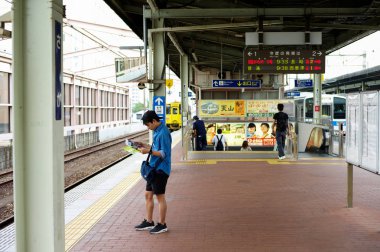 Saga, Japonya: Eylül 1, 2016 - portre Asya adam ayakta ve Saga, Japonya'nın seyahat sırasında haritaya tren istasyonu platformu