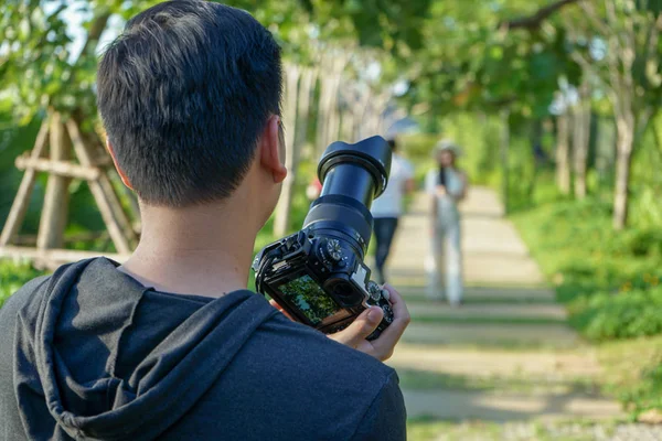 Portrait of unidentified man taking the pictuce by camera with blurred landscape in background