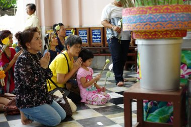 Nakhonphatom, Tayland: Eylül 19, 2016 - büyükanne ve torunu ile arka planda Budizm insan kalabalığı Budist Tapınağı'nda dua portre.