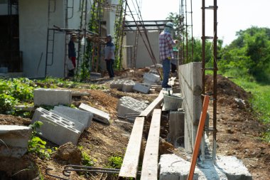 Seçici odak inşaat sahasında arka planda bulanık işçiler ile güçlendirme çelik ve çimento tuğla duvar
