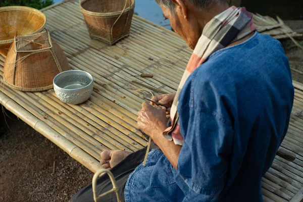 有选择地关注老人的手 通过编织天然材料制作传统的篮子 — 图库照片