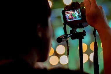 Arka planda köpüklü bokeh ışıkları ile tripod ile kamera kullanarak hareket adam bulanık. Fotoğraf çekerken adam arkasında samimi portre