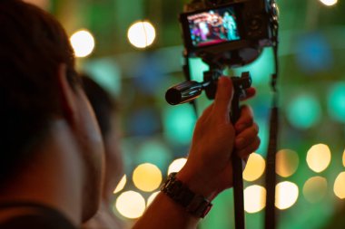 Arka planda köpüklü bokeh ışıkları ile tripod ile kamera kullanarak hareket adam bulanık. Fotoğraf çekerken adam arkasında samimi portre