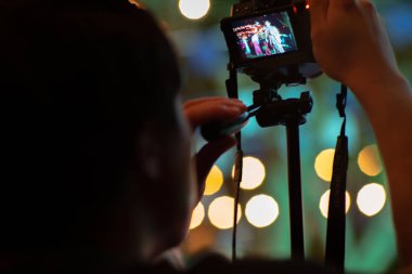 Arka planda köpüklü bokeh ışıkları ile tripod ile kamera kullanarak hareket adam bulanık. Fotoğraf çekerken adam arkasında samimi portre