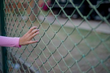 Asyalı kız elinde Seçici odak arka planda bulanık manzara ile tel örgü çit tutar