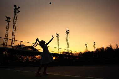 Asyalı kızın siluet portresi açık hava kortunda tenis oynuyor 
