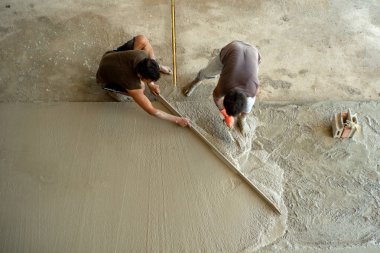 Şantiyede mala ile çimento zemin yapan işçilerin üst görünümü. Takım çalışması konsepti