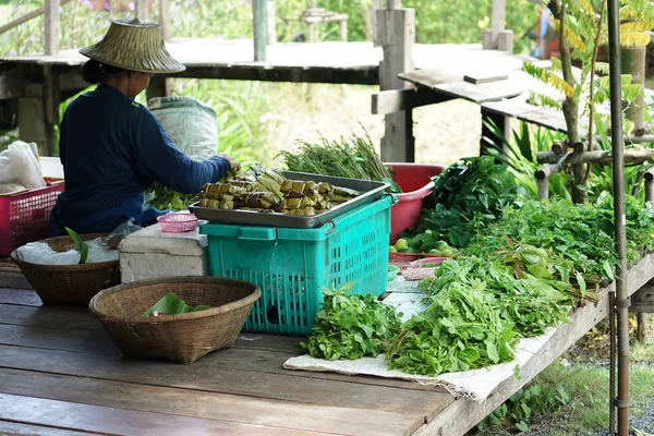 Vendedor senta-se no chão de madeira e vende o vegetal orgânico e alimentos — Fotografia de Stock