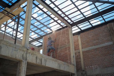 İşçi inşaat halindeki evdeki aletleri keserek duvarları kesiyor