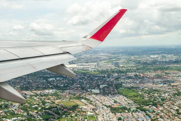 在城市景观下方的空中飞行时 飞机的遮挡翼 — 图库照片