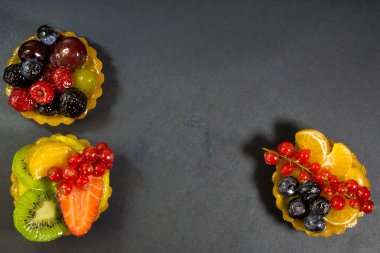 Taze biyo meyve, portakal, kivi, çilek, yaban mersini, kırmızı kuş üzümü, üzüm, ahududu, böğürtlen, yukarıda, fotoğraf ile üç kek siyah arka plan
