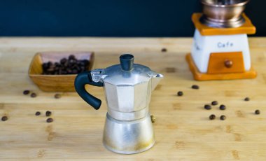 Eski İtalyan Moka kahve makinesi, el ile kahve değirmeni içinde belgili tanımlık geçmiş ve kavrulmuş kahve çekirdekleri ahşap bir tabak içinde ahşap arka plan