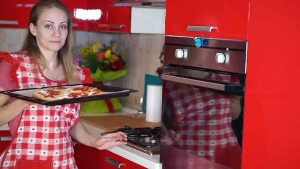 Ama de casa pone pizza en el horno para cocinar — Vídeo de stock