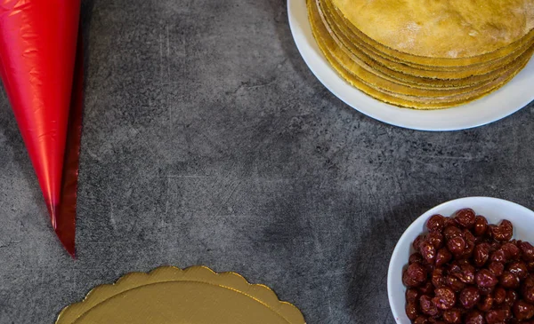 Cocinar pastel de cereza, en una mesa de piedra, galletas, bolsita de pastelería con crema, cerezas — Foto de Stock