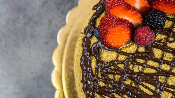 Sponge cake, chocolate on top, strawberries and raspberries — Stock Photo, Image