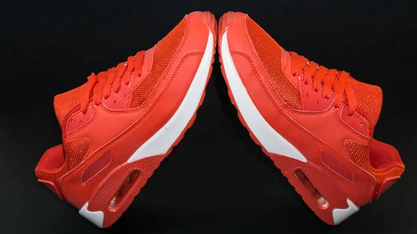 Sneakers esportes vermelho, com uma sola branca, há uma sombra, close-up em um fundo preto — Fotografia de Stock