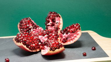 Tahıllar görünür olduğu açık nar meyve, nar arka planda mutfak taş tahtası üzerinde yer almaktadır Yeşil arka plan.