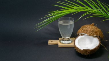 Hindistan cevizi egzotik meyve, kabuk hindistan cevizi iki yarısı, koyu bir arka plan, mutfak ve kara tahta, palmiye ağacı, seçici odak hindistan cevizi suyu bir bardak