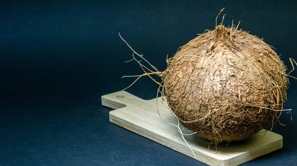 Fruta exótica de coco, frutas en la cáscara en una tabla de madera, fondo oscuro, enfoque selectivo, luz selectiva, primer plano —  Fotos de Stock