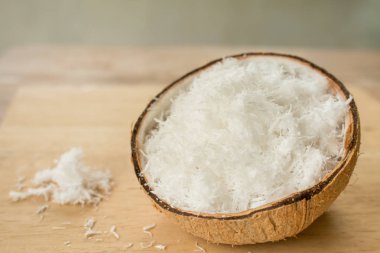 Ahşap masanın üzerinde taze rendelenmiş hindistan cevizini kabukla kapat..