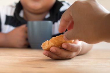 Asyalı çocuk elinde ekmek turtası tutuyor..