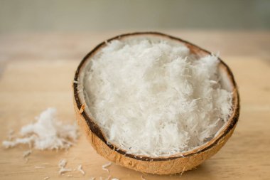 Ahşap masanın üzerinde taze rendelenmiş hindistan cevizini kabukla kapat..