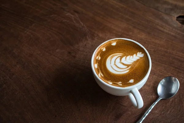 Tutup cangkir kopi seni latte panas di atas meja kayu — Stok Foto