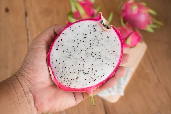 Tangan memegang buah-buahan Naga di latar belakang kayu, Diiris deliciou — Stok Foto