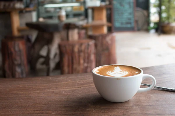 Close-up van Cup van hete latte kunst koffie op houten tafel — Stockfoto