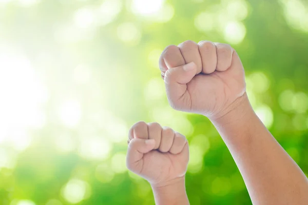 Raising hands on green natural bokeh blurred abstract background