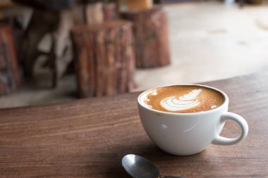 Tahta masadaki bir fincan sıcak latte sanat kahvesi.