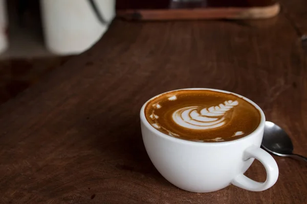 Tutup cangkir kopi seni latte panas di atas meja kayu — Stok Foto